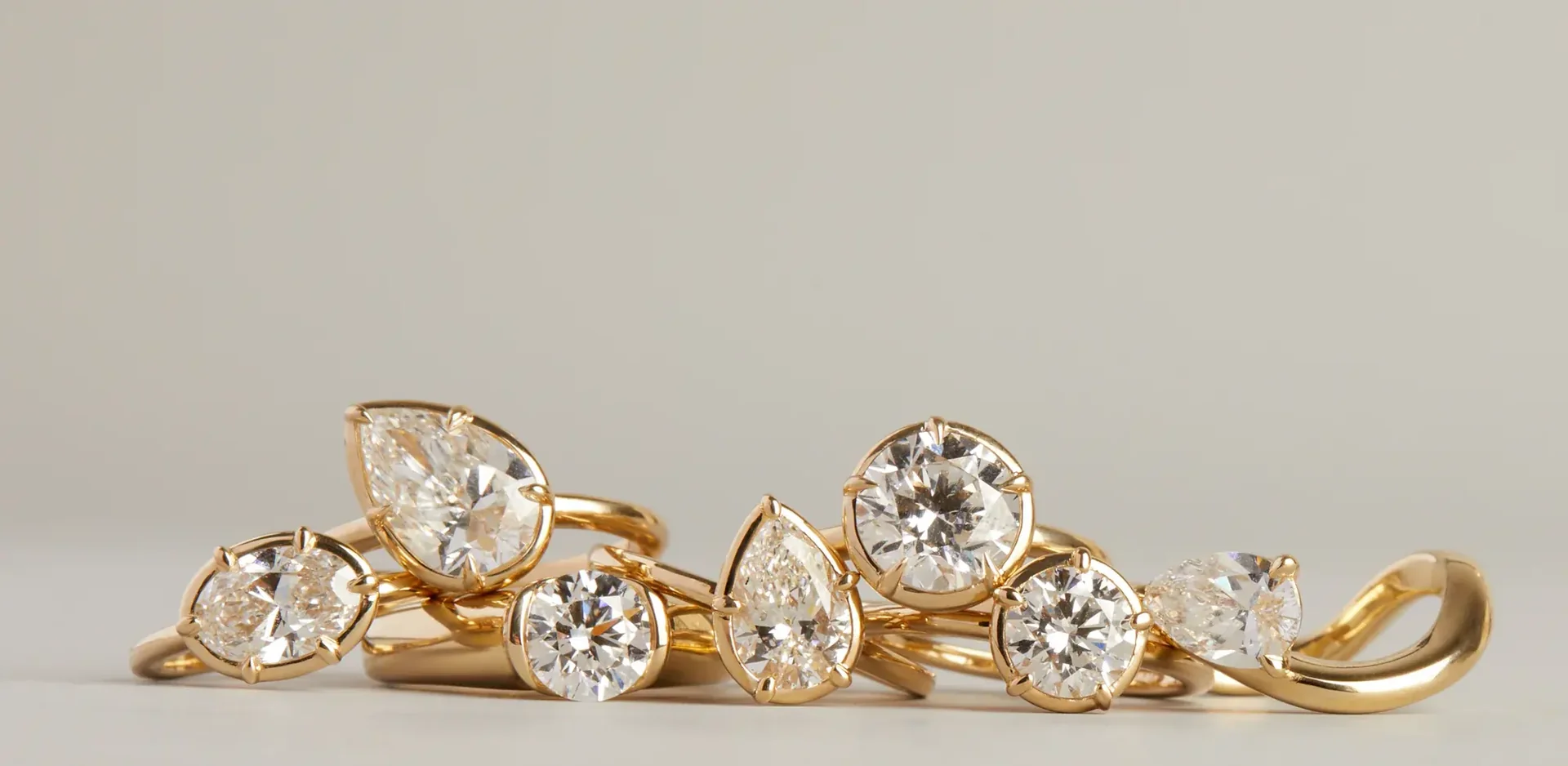 A row of solitaire rings in 18k gold lined up on the atelier bench