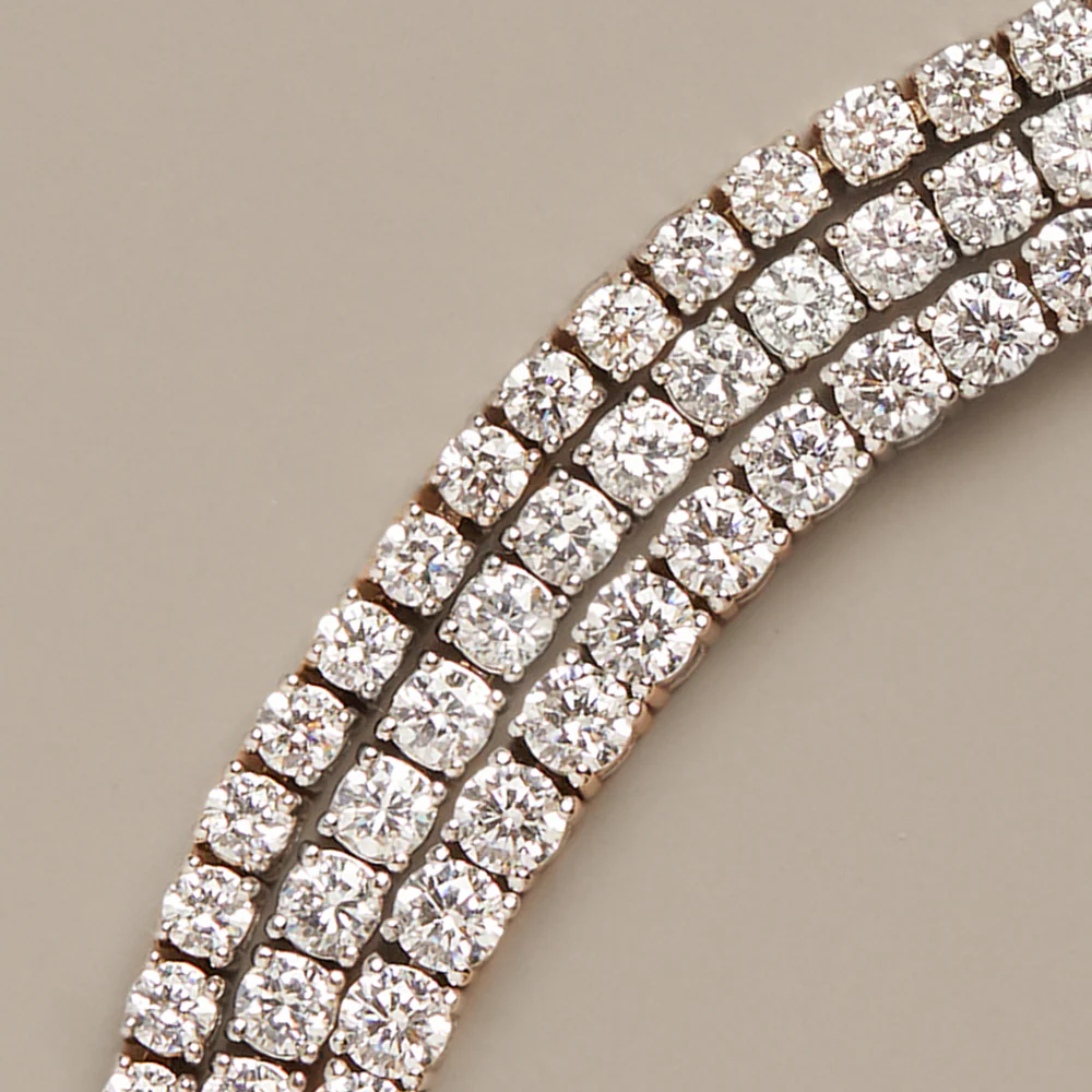 Macro photograph of three rows of round brilliant lab-grown diamonds in claw settings