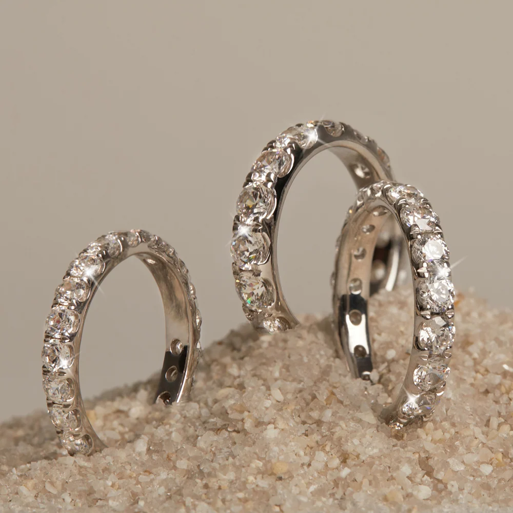 Three pavé diamond eternity bands resting in sand